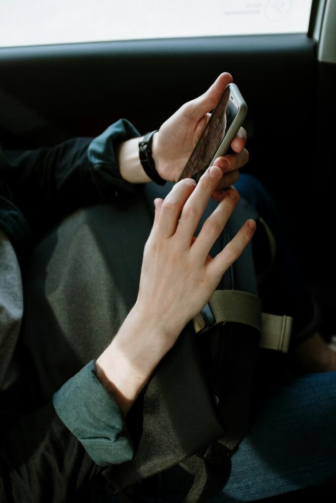 pexels-photo-4606337-4606337 A man interacts with his smartphone while seated in a car, capturing modern transportation and lifestyle.